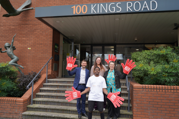 group including Adham in front of House of Fisher holding red foam Catch the Bus Month hands
